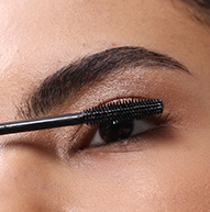 Image en gros plan d'une personne appliquant du mascara noir Nanolash sur ses cils supérieurs à l'aide d'une baguette.