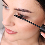 Une femme utilise habilement une brosse à mascara pour appliquer le mascara, en se concentrant sur ses cils pour obtenir un look défini.