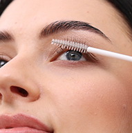 Une femme utilise un pinceau pour appliquer le mascara, rehaussant méticuleusement ses cils pour obtenir une apparence polie et sophistiquée.