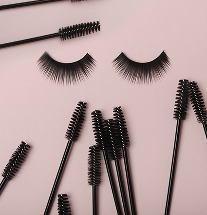Deux cils au centre, entourés de baguettes de mascara sur fond rosé